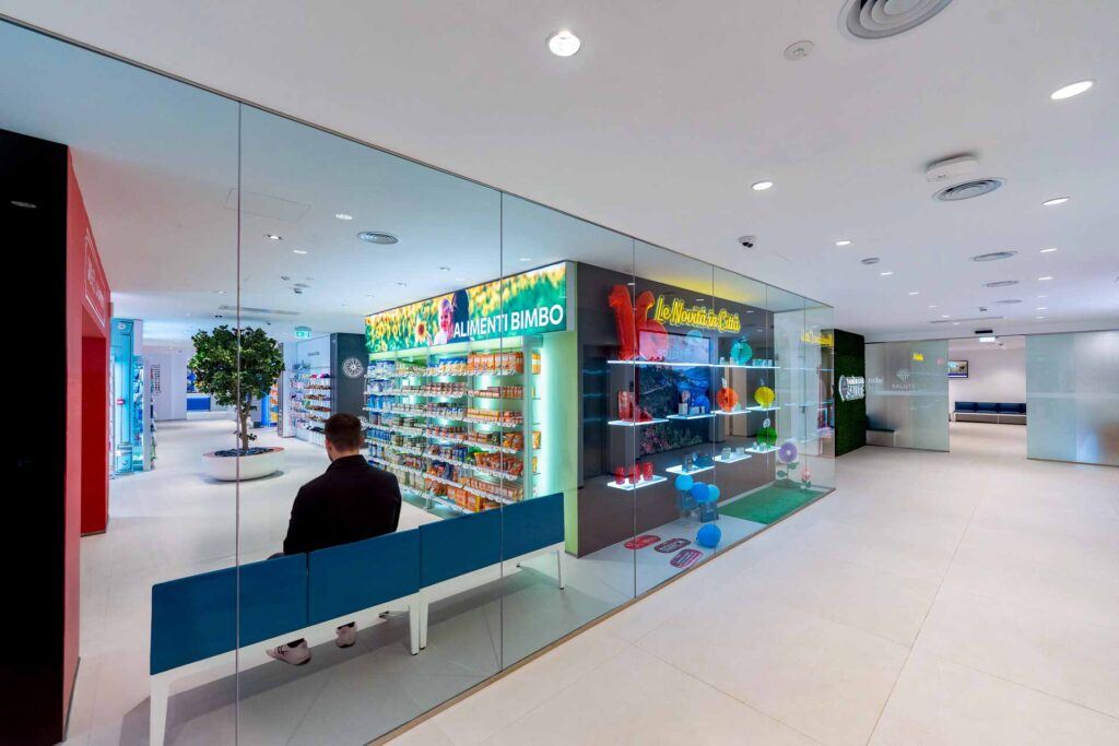 Area di attesa separata da pareti in vetro, affacciata sul reparto alimenti per bambini della Farmacia Scoccianti.